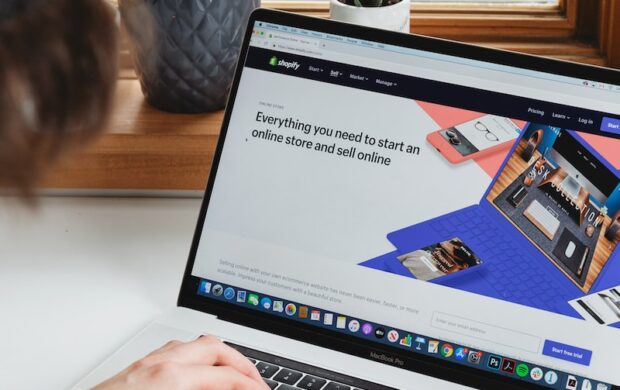 person using macbook pro on white table