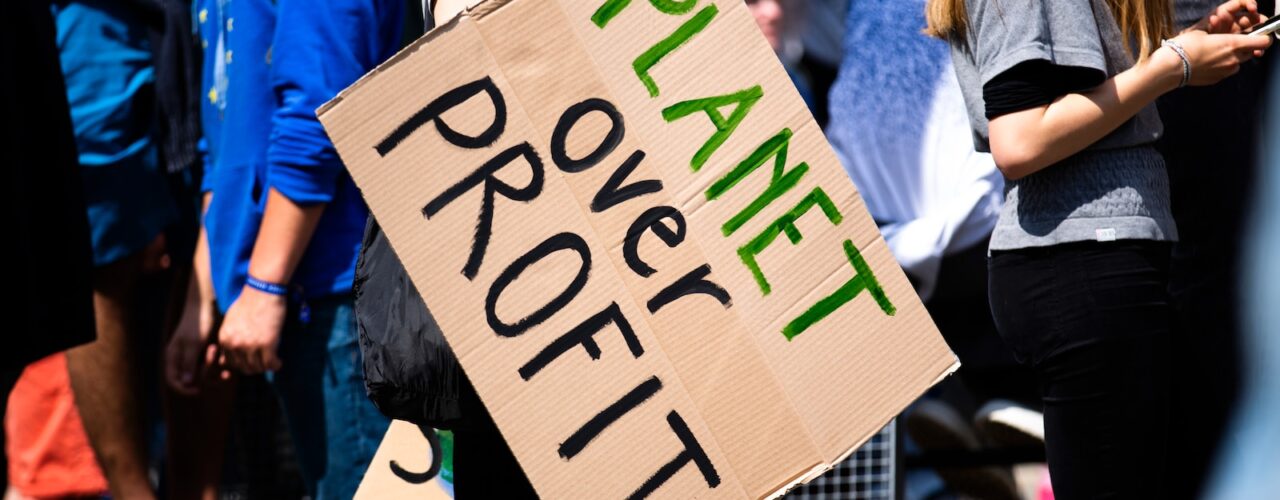 woman holding Planet over Profit placard