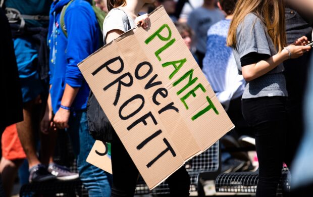 woman holding Planet over Profit placard