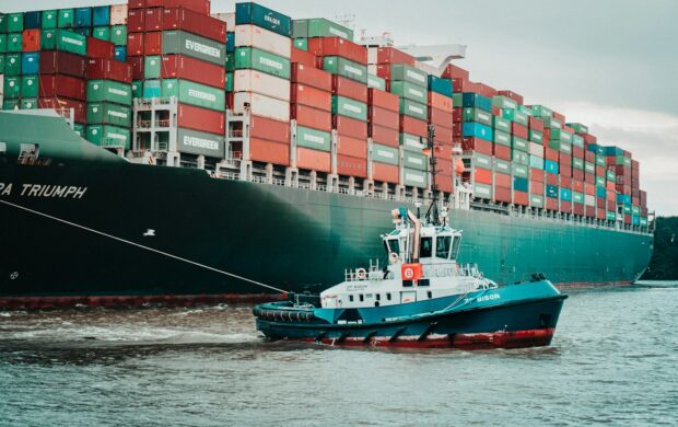 a tug boat pulling a large container ship